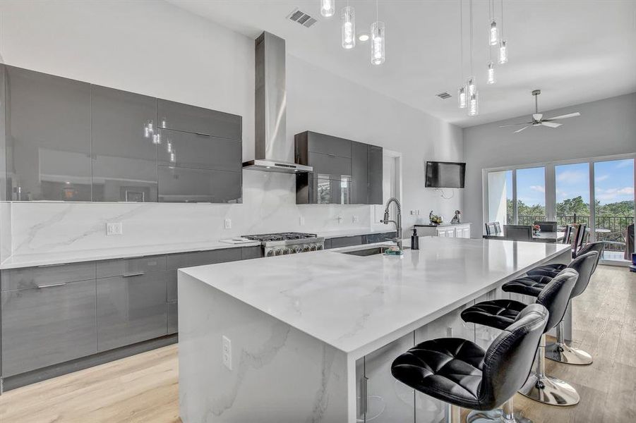 Kitchen featuring modern cabinets, gray cabinetry, a large island, a breakfast bar, and light wood-type flooring