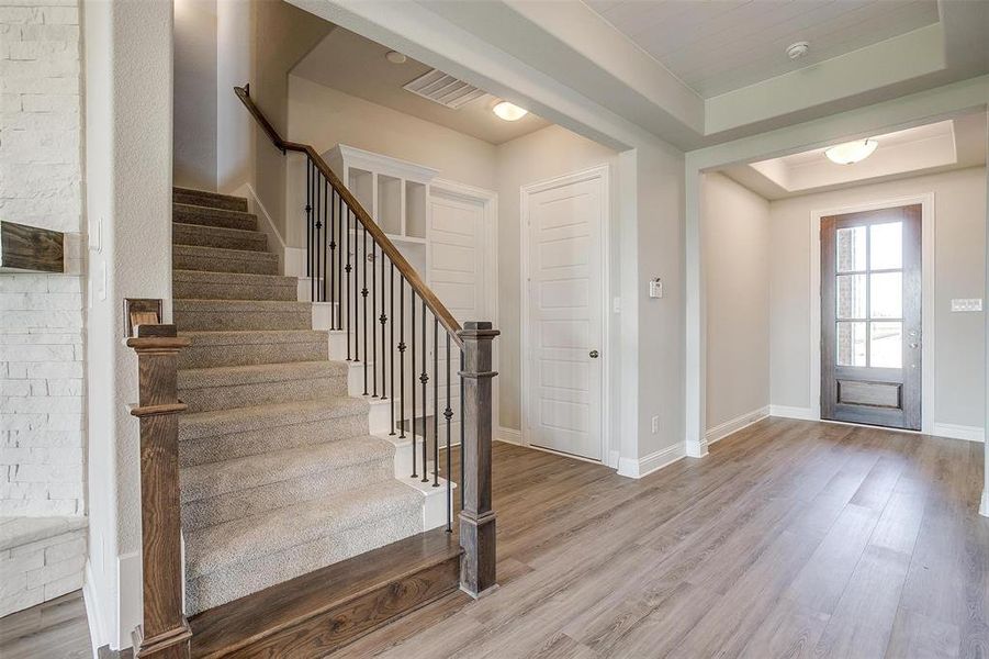 Foyer entrance with wood-type flooring and a tray ceiling