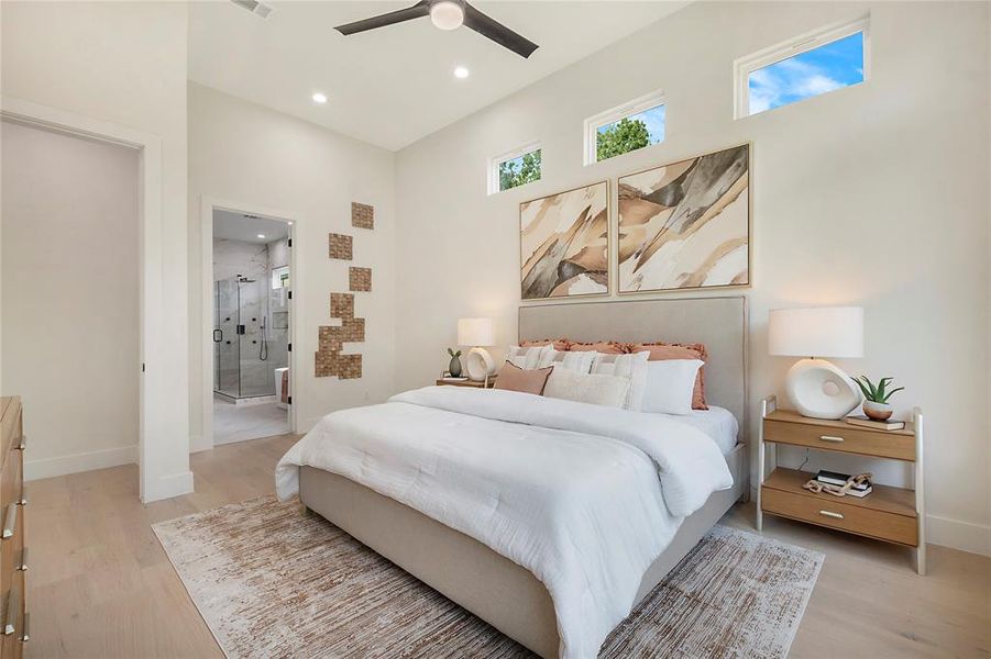 Bedroom with ensuite bathroom, light wood-type flooring, and ceiling fan