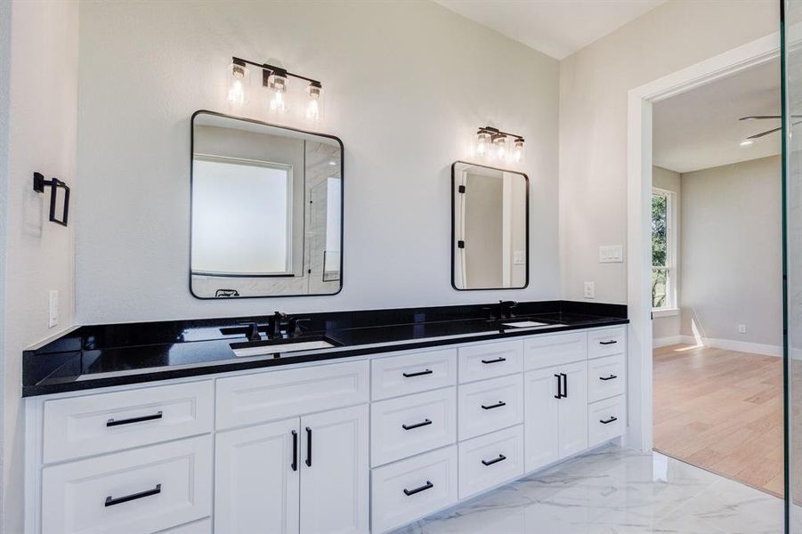 Double vanity with white cabinetry, black countertops, and matte black hardware