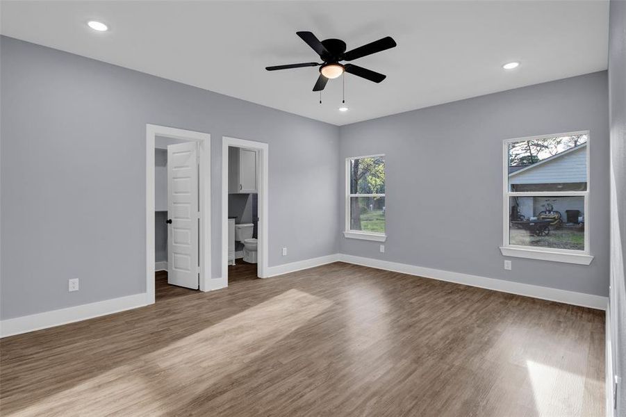 Unfurnished bedroom with a walk in closet, dark wood-style flooring, recessed lighting, and a ceiling fan