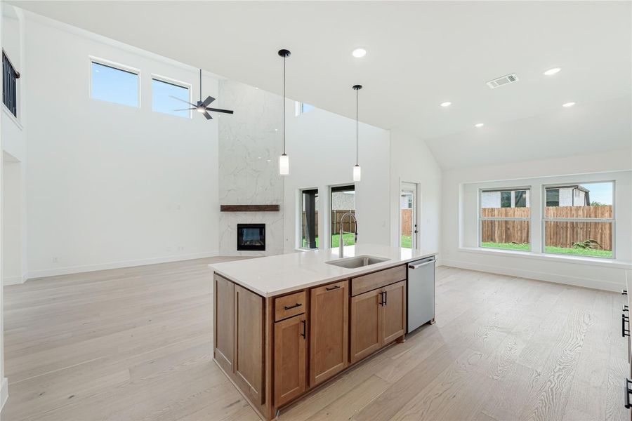 Open-concept kitchen with wood island, quartz countertop, and vaulted ceiling overlooking living area with stone fireplace Open-concept kitchen with wood island, quartz countertop, and vaulted ceiling overlooking living area with stone fireplace