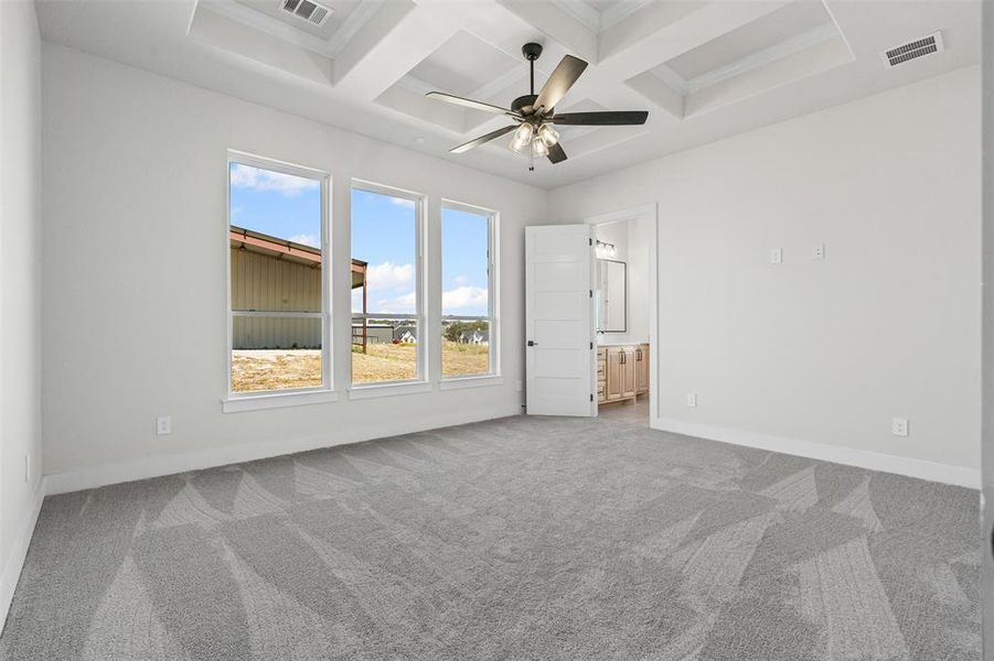 Unfurnished bedroom with carpet floors, connected bathroom, coffered ceiling, beamed ceiling, and a ceiling fan