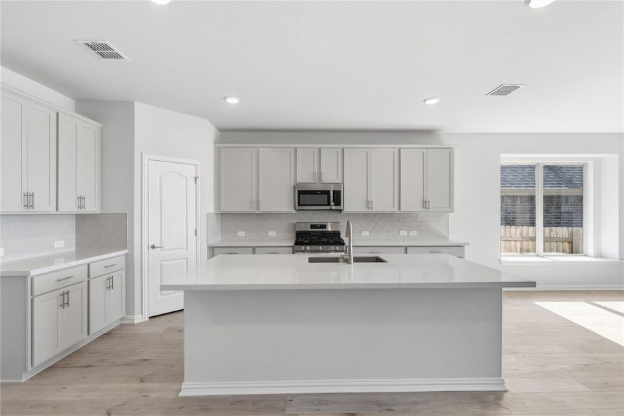 Kitchen with backsplash, appliances with stainless steel finishes, a center island with sink, light stone countertops, and recessed lighting Kitchen with backsplash, appliances with stainless steel finishes, a center island with sink, light stone countertops, and recessed lighting