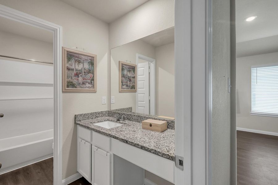 Secondary bath with separate sink area with a vanity.  Shower features wall inset.