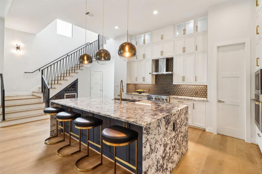 Cabinetry is built to-the-ceiling and decorative lighting enhances the glassfront cabinets on the upper row. The walk in pantry is tucked to the left of the oven.