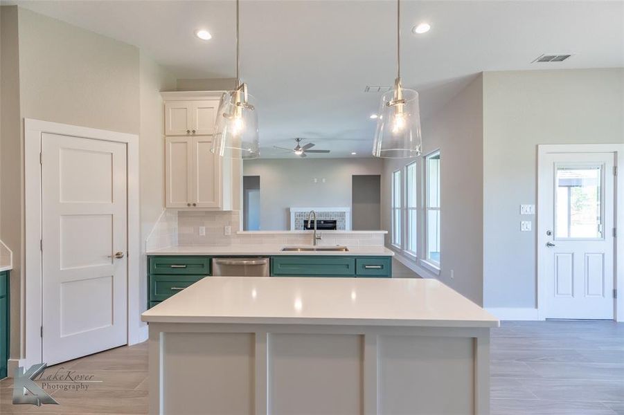 Kitchen featuring healthy amount of natural light, ceiling fan, light countertops, white cabinetry, and recessed lighting