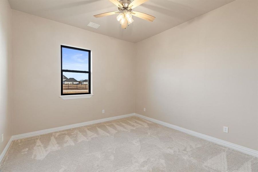 Empty room with ceiling fan and light colored carpet