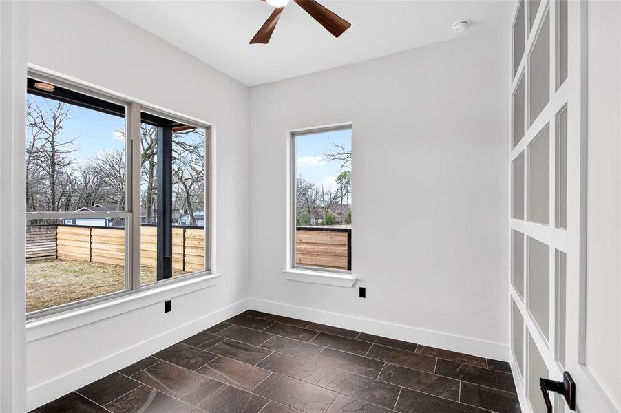 Spare room featuring a ceiling fan and dark stone finish flooring