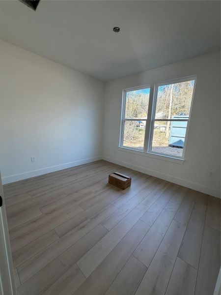 Spare room featuring baseboards and light wood-type flooring