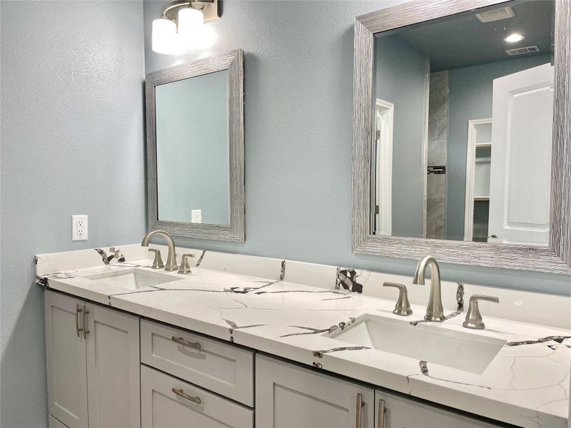A refined bathroom featuring dual sinks with modern fixtures, set against a calming blue wall.