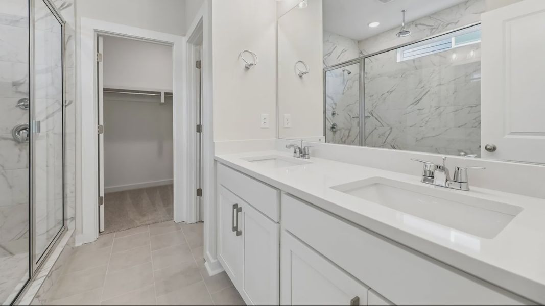 Primary bathroom with dual vanity and access to closet
