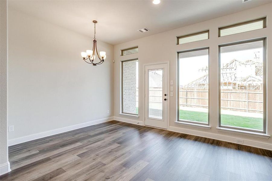 Empty room featuring dark wood-type flooring and a notable chandelier