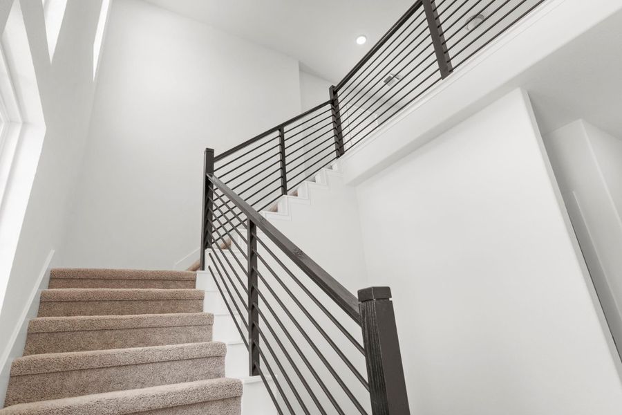 Elegant two-story staircase with modern cable railing and plush carpet leading to the upper level.
