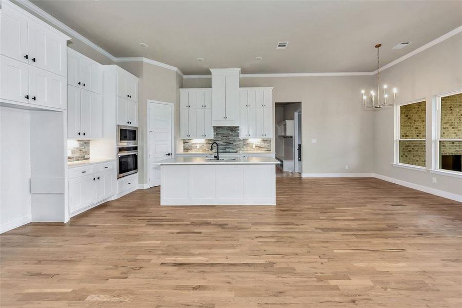 Kitchen featuring white cabinets, backsplash, light hardwood / wood-style floors, and appliances with stainless steel finishes