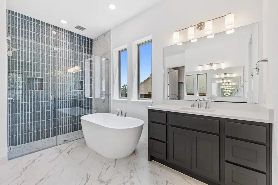 Full bathroom featuring vanity, walk in shower, a freestanding tub, light marble finish flooring, and recessed lighting