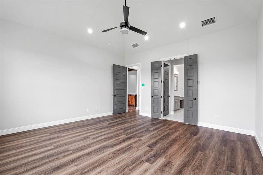 Unfurnished bedroom featuring connected bathroom, dark wood-type flooring, and ceiling fan