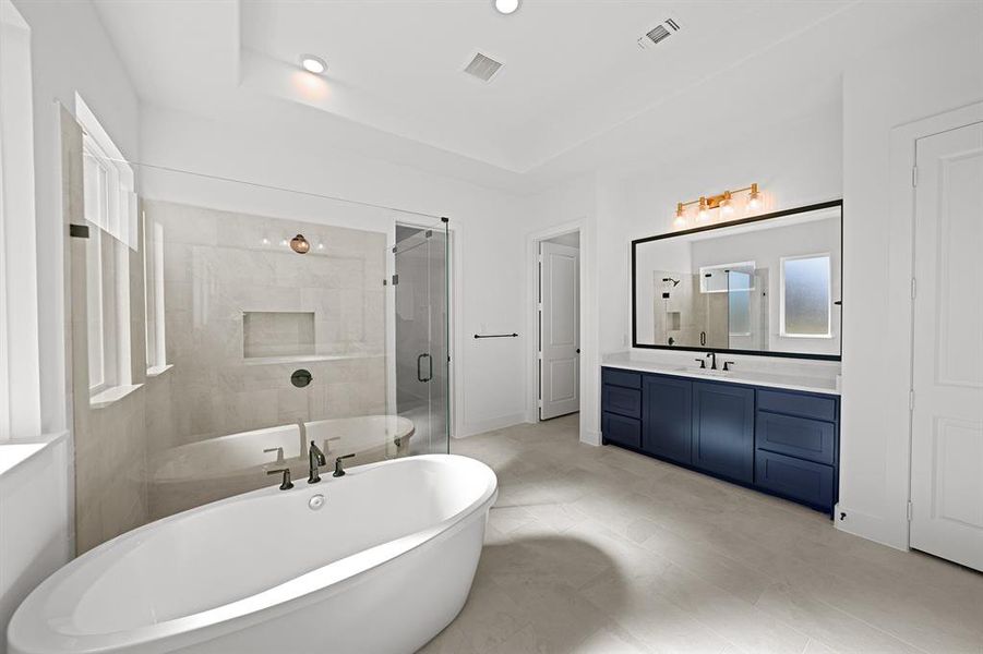 Full bathroom with vanity, a freestanding bath, a shower stall, recessed lighting, and a tray ceiling Full bathroom with vanity, a freestanding bath, a shower stall, recessed lighting, and a tray ceiling