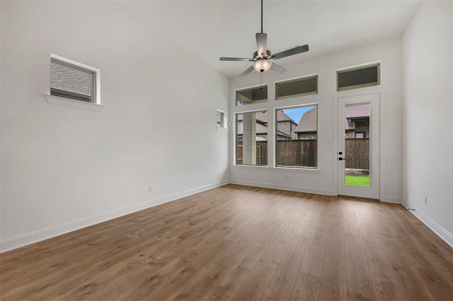 Spacious room featuring wood-finish flooring, high ceilings, and a modern ceiling fan with integrated lighting