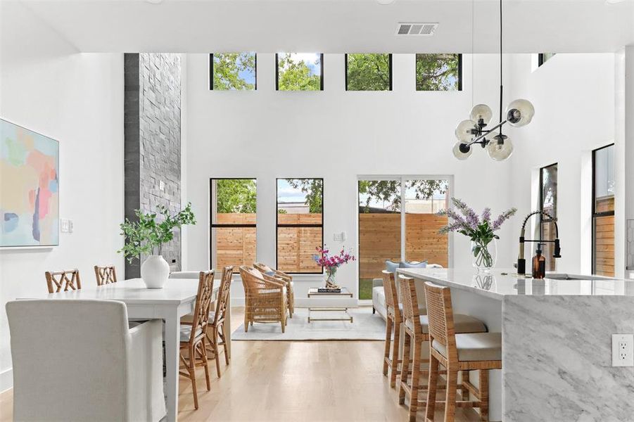 Dining space featuring light hardwood / wood-style flooring, sink, and a towering ceiling