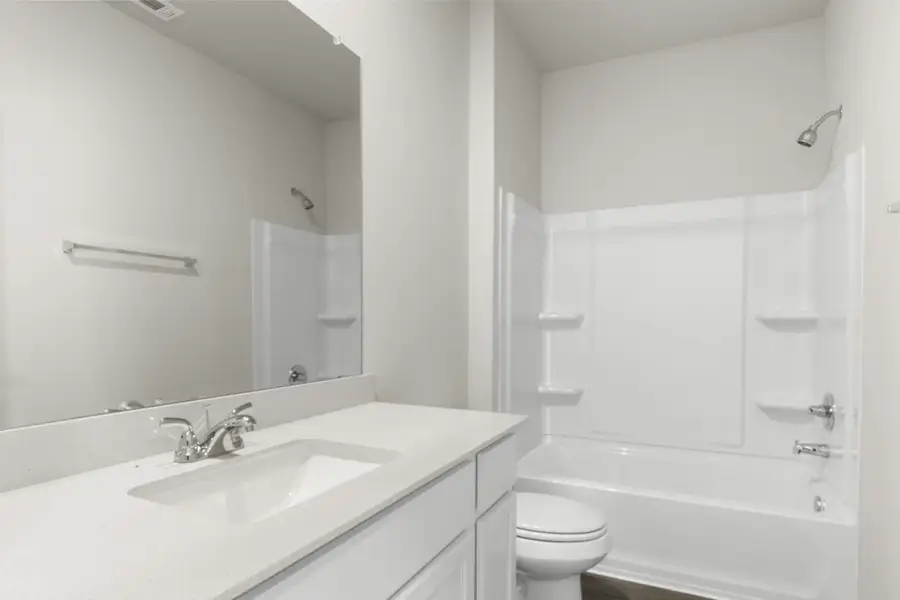 Image of a bathroom with white cabinets and vanity, a large mirror and a white shower and tub