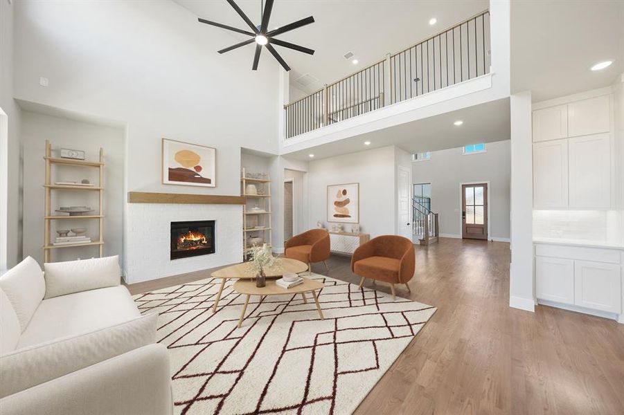 Living room with built in features, a glass covered fireplace, a towering ceiling, light wood-style floors, and recessed lighting Living room with built in features, a glass covered fireplace, a towering ceiling, light wood-style floors, and recessed lighting