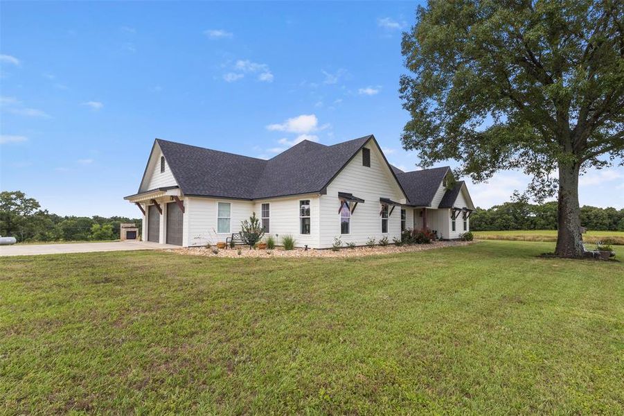 Beautiful custom farmhouse-style exterior set on expansive acreage, featuring inviting curb appeal, wide-open surroundings, mature trees, and a peaceful East Texas setting.
