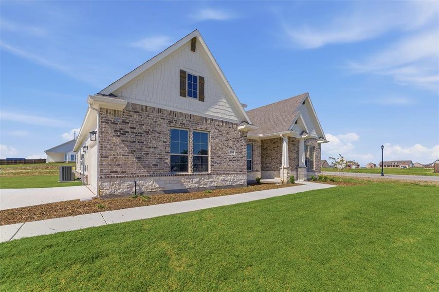 Contemporary exterior featuring a brick and stone facade, gabled rooflines, and a covered entry porch supported by substantial columns