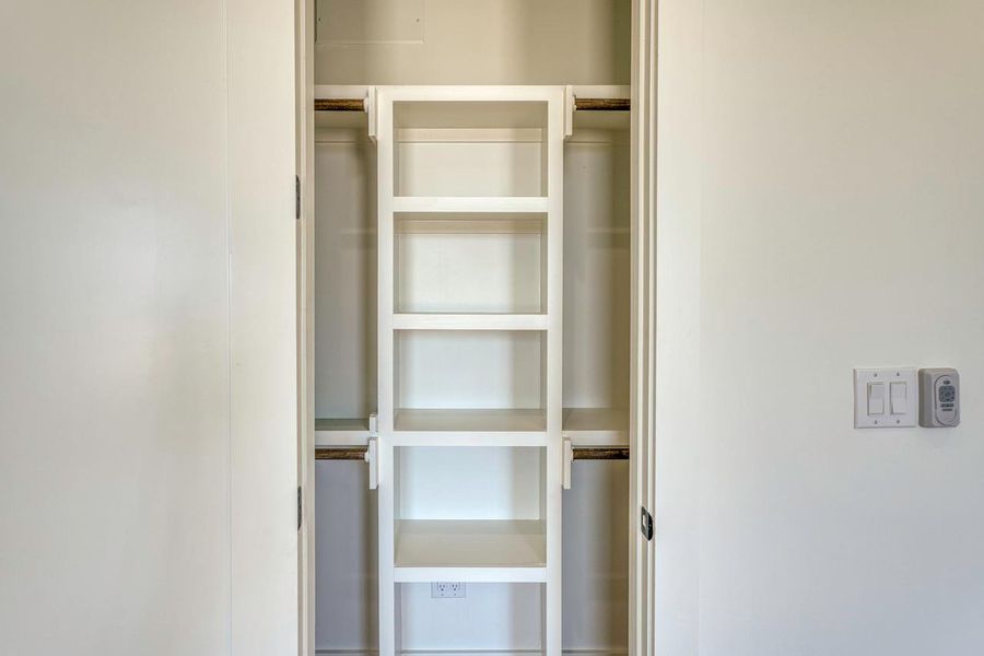 Custom built-in shelving and hanging rods maximize storage efficiency within this functional closet space.