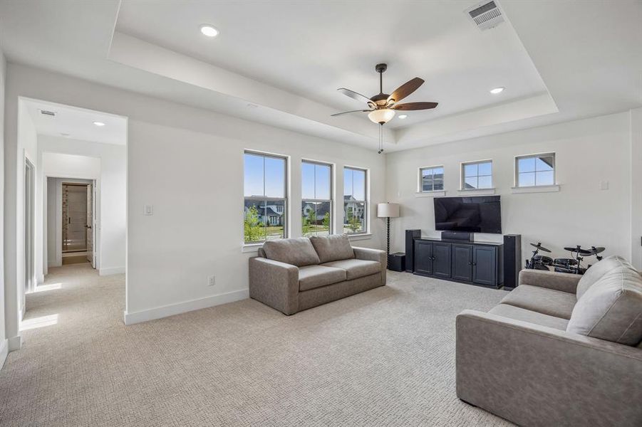 Living room with light colored carpet, a tray ceiling, ceiling fan, and recessed lighting