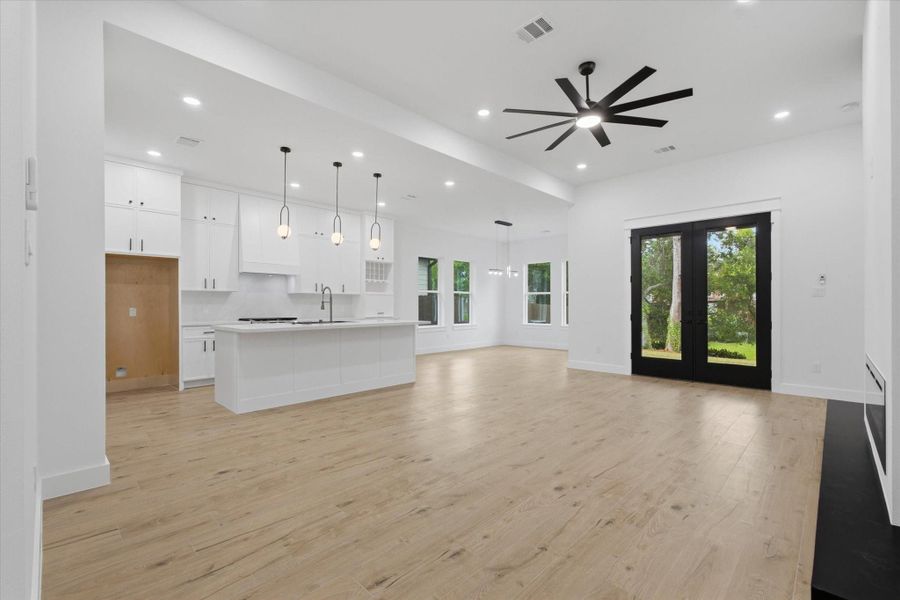 Modern Elegance & Scale. Experience the true definition of open-concept living. This expansive great room boasts high ceilings, a dramatic oversized minimalist ceiling fan, and seamless transitions between the gourmet kitchen, dining space, and the outdoors through massive double glass patio doors.