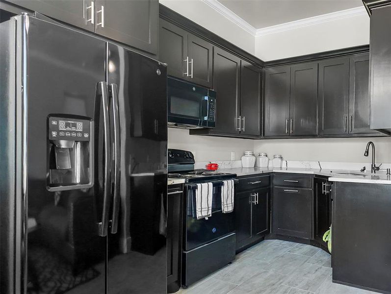 Kitchen featuring black appliances, crown molding, dark cabinetry, and light stone counters