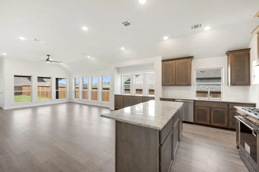 Open kitchen with dark wood cabinets, granite island, and hardwood floors flowing into living area Open kitchen with dark wood cabinets, granite island, and hardwood floors flowing into living area