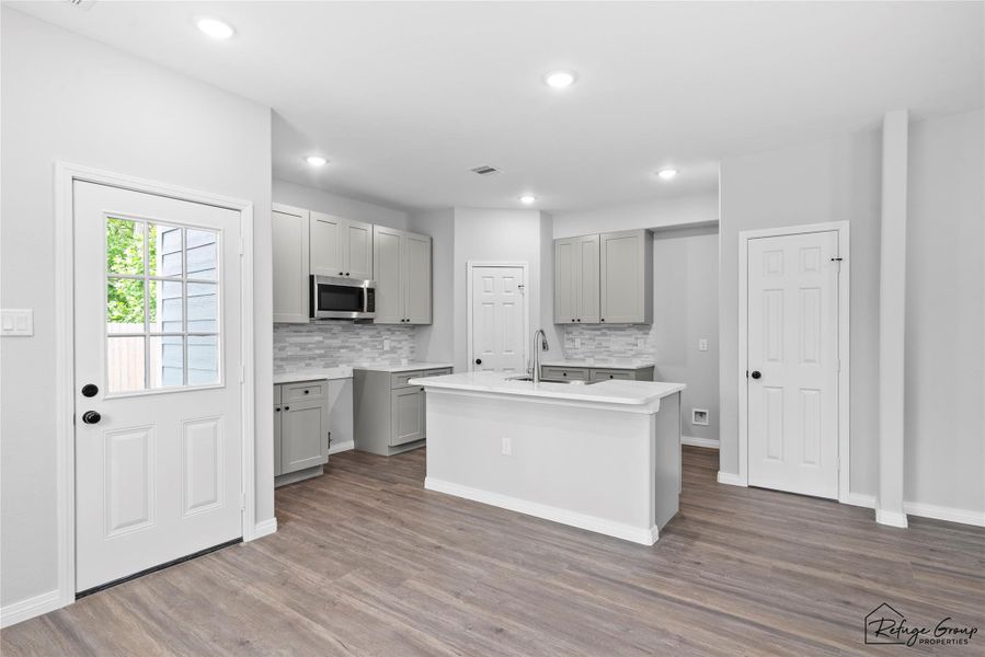 Kitchen features stainless steel microwave and gas stove (to be installed prior to closing) as well as an island with Quartz countertops Kitchen features stainless steel microwave and gas stove (to be installed prior to closing) as well as an island with Quartz countertops