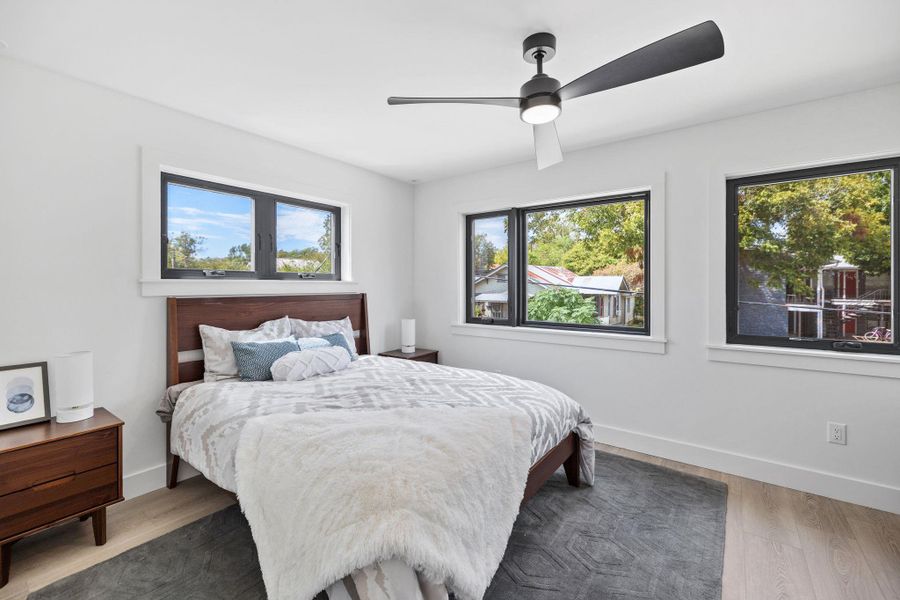 Bedroom with wood finished floors, multiple windows, and ceiling fan