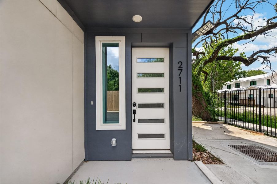 Modern front entry with a sleek design, featuring a white door with horizontal glass panels and a vertical window. The exterior has a clean, contemporary look, with a small porch area and a visible street number. Modern front entry with a sleek design, featuring a white door with horizontal glass panels and a vertical window. The exterior has a clean, contemporary look, with a small porch area and a visible street number.