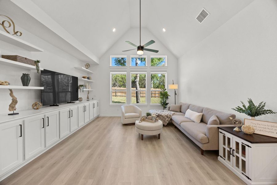 Living area with a high ceiling, light wood-style flooring, ceiling fan, and recessed lighting