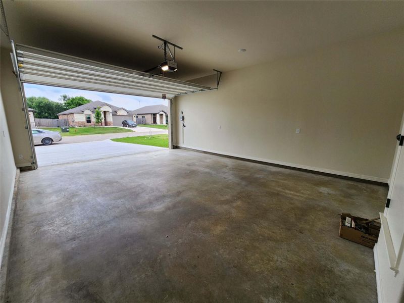 Spacious garage with an automatic overhead door, concrete flooring, and painted walls