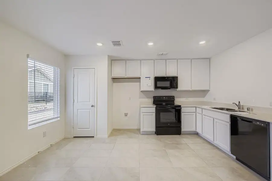 Kitchen featuring light countertops, white cabinets, black appliances, recessed lighting, and open floor plan