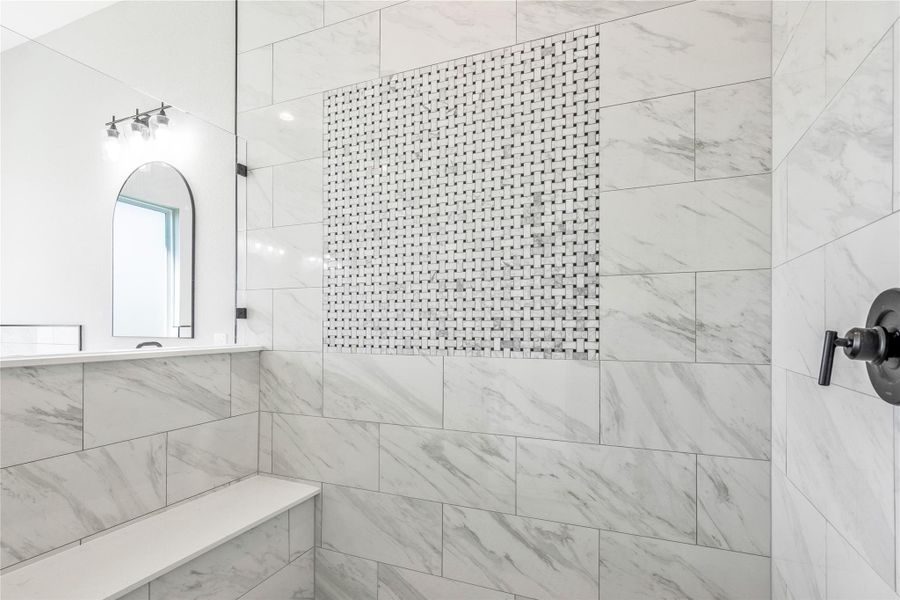 Luxurious walk-in shower featuring a built-in bench and stunning tile design.