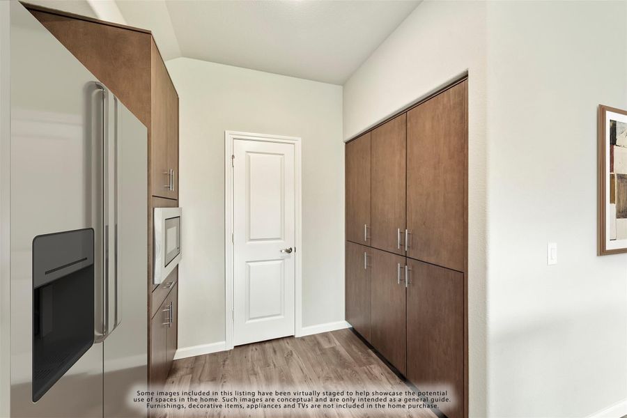 Kitchen area with dark wood cabinets, built-in microwave, stainless steel refrigerator, and light wood floors