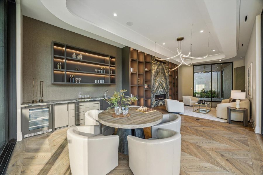 Walls of glass frame captivating views of the lush lawn and sparkling pool, flooding this stylish dining and entertaining area with natural light. Features include Ocean Fantasy Francini quartzite countertops, a panel-front mini fridge and icemaker, and tray ceilings with recessed LED lighting and built-in speakers.