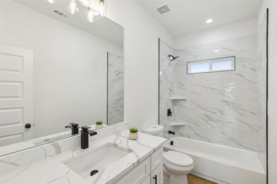 Full bathroom with vanity, toilet, and tiled shower / bath combo