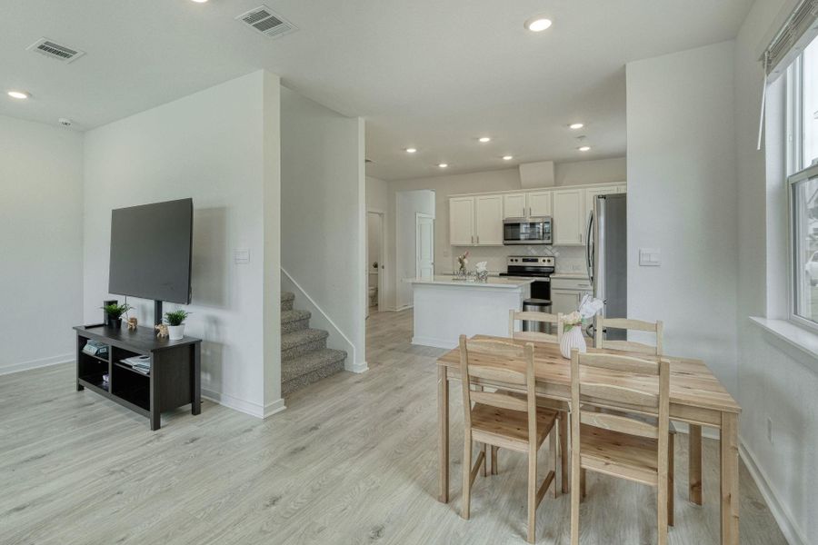 Dining area with light wood-style flooring, stairway, visible vents, and recessed lighting