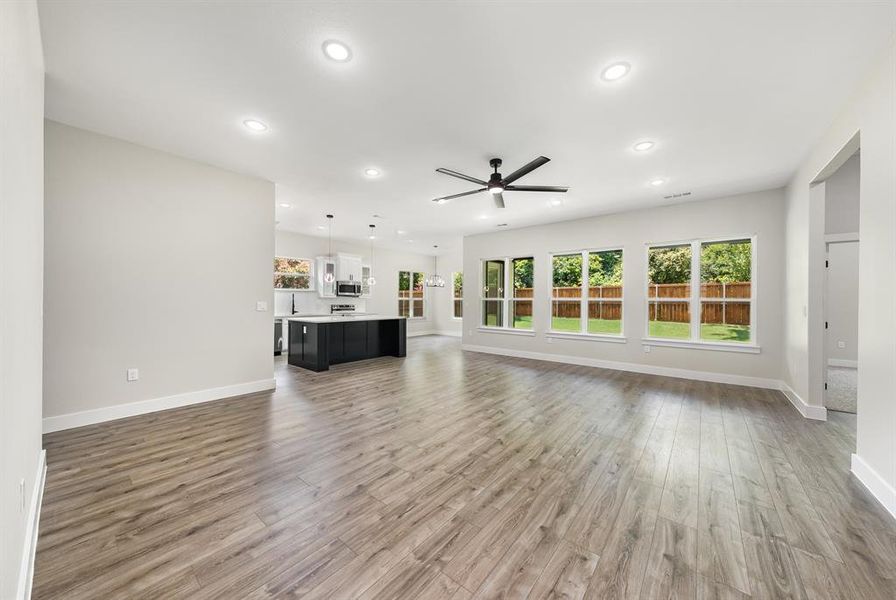 Unfurnished living room with ceiling fan, healthy amount of natural light, light wood-style flooring, and recessed lighting Unfurnished living room with ceiling fan, healthy amount of natural light, light wood-style flooring, and recessed lighting