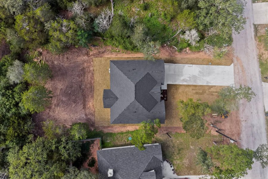 An aerial perspective reveals a contemporary home nestled among verdant trees with a spacious driveway.
