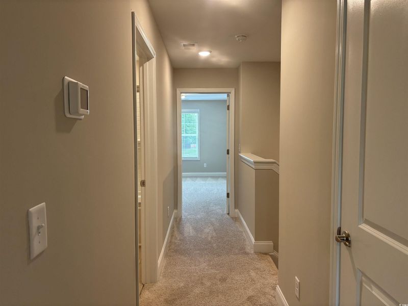 Corridor featuring light colored carpet and baseboards