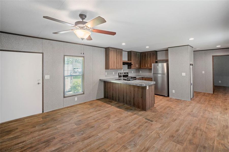 Kitchen featuring stainless steel appliances, a peninsula, light countertops, a ceiling fan, and light wood-style flooring