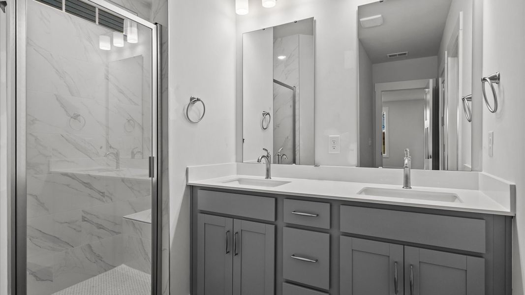 Highly functional and elegant en-suite with dual vanities, tiled walk-in shower, and refined finishes