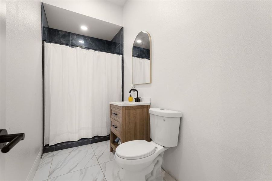Bathroom featuring a shower with dark tiled surround, white shower curtain, and recessed lighting Bathroom featuring a shower with dark tiled surround, white shower curtain, and recessed lighting